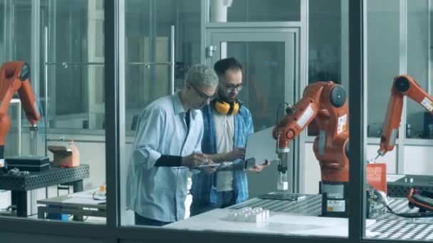 İki araştırmacının bir robot mekanizmasını test ettiği bir laboratuvar. — Stok video