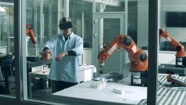 Il giovane specialista in VR-occhiali sta controllando un braccio robotico in movimento — Video Stock