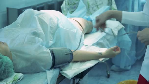 Ένας γιατρός παίρνει τους ασθενείς αρτηριακή πίεση σε ένα χειρουργικό δωμάτιο. — Αρχείο Βίντεο