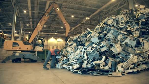 電子ゴミリサイクル工場。埋め立て検査官が山のゴミを調べてる — ストック動画