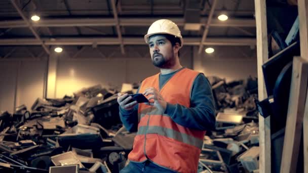 Schrottplatz-Einheit, in der ein männlicher Spezialist ein Telefon bedient — Stockvideo