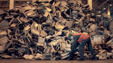 Elektronik çöp geri dönüşüm fabrikası. Atık depolama müfettişi çöp yığınına atık atıyor.