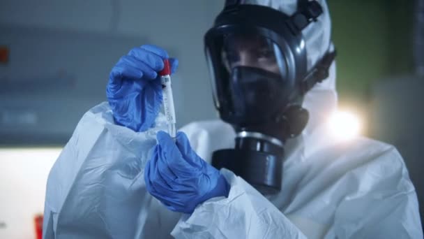 Um tubo de teste covid-19 está sendo examinado por uma pessoa em um terno hazmat. Conceito de Coronavirus 2019-nCoV . — Vídeo de Stock