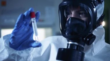 Sıçrama giysisi giymiş bir araştırmacı kovid 19 test tüpünü inceliyor. Coronavirus COVID-19 konsepti.