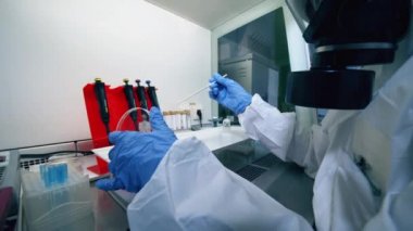 Coronavirus 2019-nCoV konsepti. Kimyasal madde deneyi tehlikeli madde kıyafeti giyen bir kadın tarafından tutuluyor.