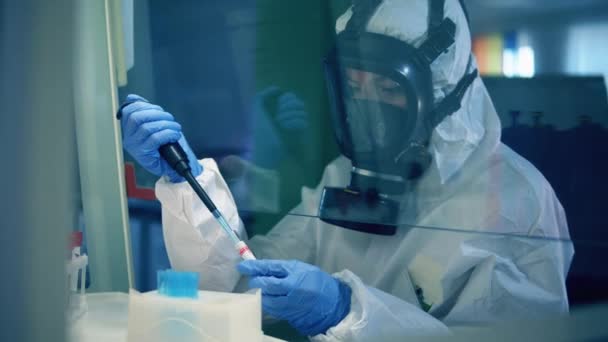 Coronavirus COVID-19 concept. Une femme en combinaison d'éclaboussure travaille avec des éprouvettes dans un laboratoire — Video