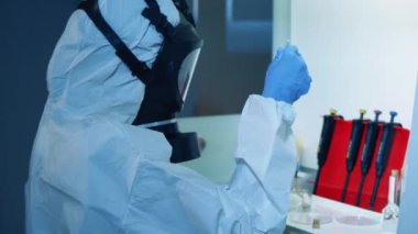 Koruyucu giysili laboratuvar çalışanı bir Coperid-19 sondası üzerinde çalışıyor. Coronavirus COVID-19 konsepti.