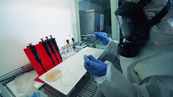 Lab worker in a hazmat suit is holding biochemical tests — Stock Video