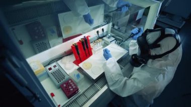 Sıçrama giysisi uzmanı laboratuvar kutusunda sondalar üzerinde çalışıyor. Coronavirus 2019-nCoV konsepti.