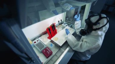 Test tüpleri koruyucu giysili bir laboratuvar çalışanı tarafından analiz ediliyor. Epidemiyoloji uzmanı Coronavirus COVID-19 numuneleri üzerinde çalışıyor. Küresel Salgın Konsepti.