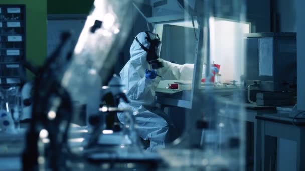 Trabajador de laboratorio en un traje de materiales peligrosos está sosteniendo pruebas de covid-19 — Vídeos de Stock