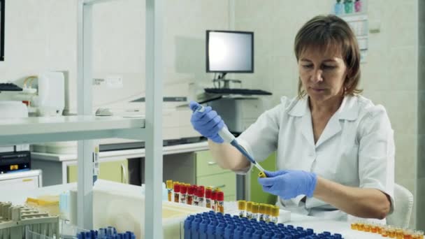 Trabajadora de laboratorio está reubicando muestras biológicas entre tubos de ensayo — Vídeo de stock