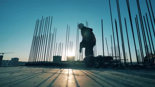 Un hombre usa un taladro en un sitio de construcción . — Vídeos de Stock