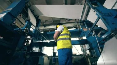 Fabrika müfettişi ekipmanların arasından geçen kağıtları inceliyor.