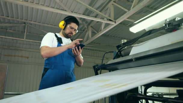 Ingénieur avec un smartphone observe le transport du papier — Video