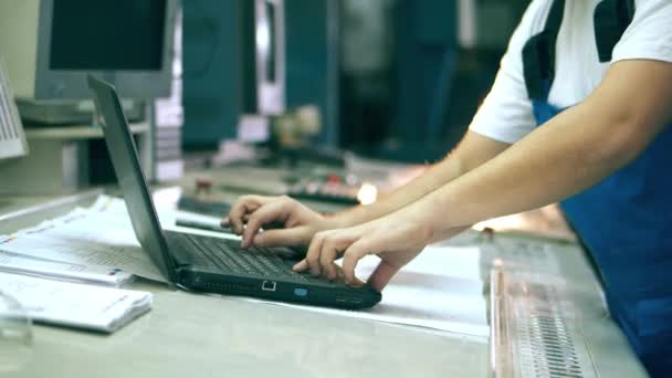 Laptop en een mannelijke ingenieur typen erop in een fabriekseenheid — Stockvideo