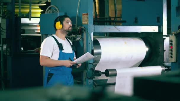 Inspetor de fábrica está tomando notas enquanto observa o equipamento — Vídeo de Stock