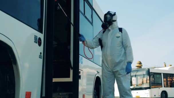Απολυμαντικό σε ένα κοστούμι splash απολυμαίνει την έξοδο του λεωφορείου. Πανδημία του Coronavirus έννοια, διαδικασία απολύμανσης. — Αρχείο Βίντεο