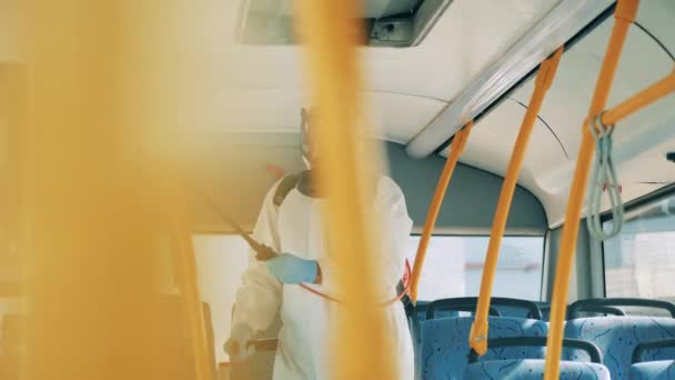 A busz belsejének kémiai kezelését egy fertőtlenítő végzi. Coronavirus pandémia koncepció, fertőtlenítési folyamat. — Stock videók