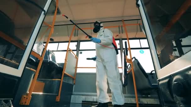 A person in a protection suit is doing chemical treatment in a bus — Stock Video