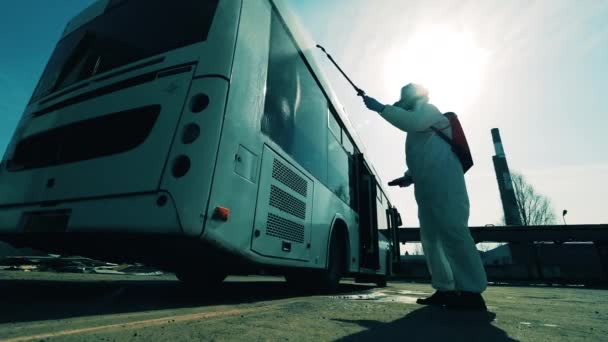 Працівник дезінфекції омолоджує автобус ззовні — стокове відео