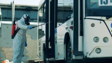 Temizlik işçisi tarafından tutulan bir otobüs çıkışındaki dezenfeksiyon.