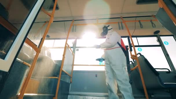 Koronavirová pandemie, dezinfekce. Specialista dezinfikuje interiér sběrnice chemikáliemi — Stock video