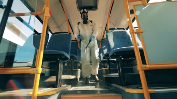 Le désinfecteur marche le long du bus et le désinfecte. Prévention du coronavirus, processus de désinfection sanitaire . — Video