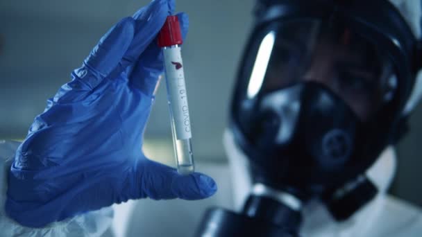 Biologist in protection suit looks at a tube with negative coronavirus result. — Stock Video