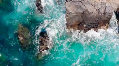 Kıyıdaki kayalıklara vuran mavi dalgalar.