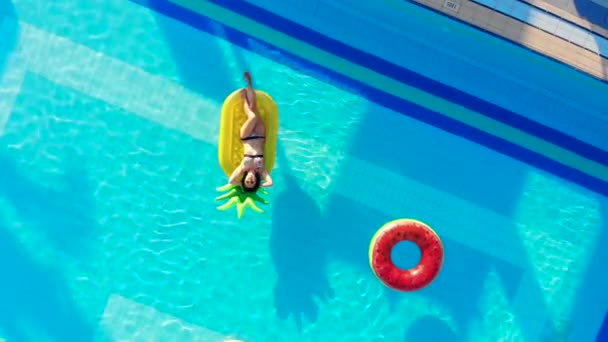Uma menina descansa em uma piscina de hotel com anéis de borracha . — Vídeo de Stock