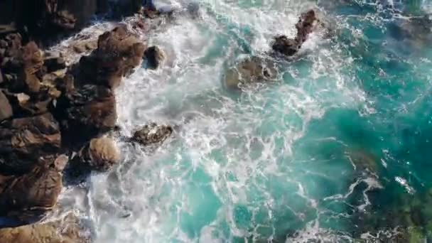 Τυρκουάζ θάλασσα πιτσιλίζει σε βράχια σε μια ακτή. — Αρχείο Βίντεο