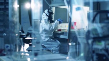 Koruyucu kıyafetli araştırmacı bir aşı üretiyor..