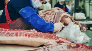 Fabrika işçileri büyük et parçaları kesiyorlar. Et işleme tesisi