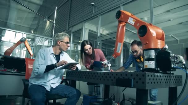 Roboter zeichnet unter Aufsicht junger Ingenieure — Stockvideo