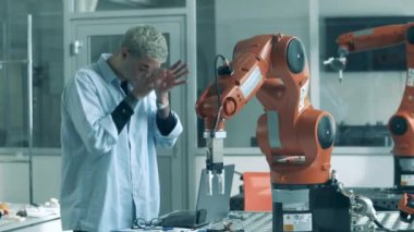 Koruyucu gözlüklü laboratuvar asistanı bir robotu gözlemliyor.