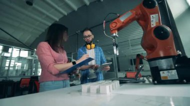 İki mühendis bir robotla yapılan bir deneyin notlarını alıyor.