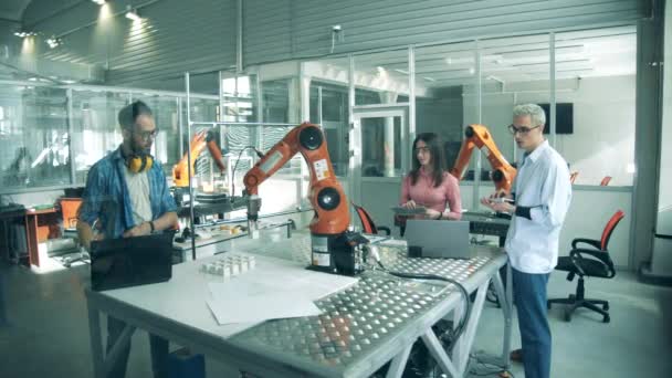 En grupp studenter, unga ingenjörer testar robotar. Laboratorium med forskare som testar robotmekanismer — Stockvideo