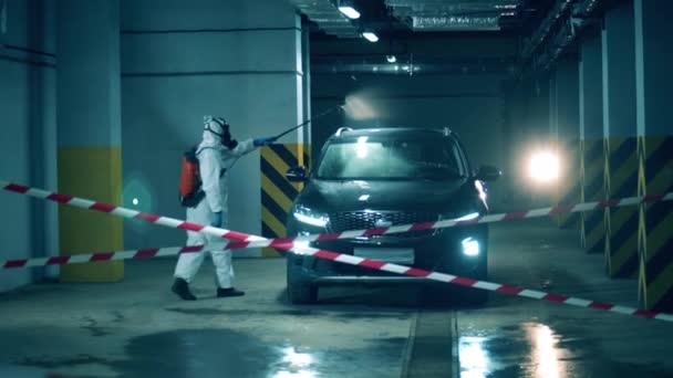 Koronavirus, koncept dezinfekce. Sanitář dezinfikuje auto na parkovišti. — Stock video