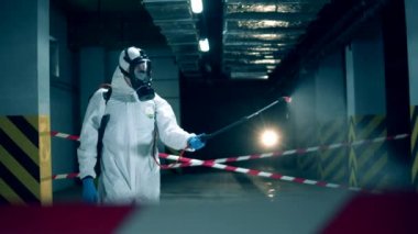 Coronavirus, dezenfeksiyon konsepti. Tehlikeli madde giysisi uzmanı boş bir üniteyi dezenfekte ediyor.