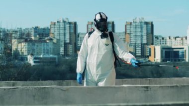 Dezenfeksiyon işçisi sokağa kimyasal püskürtüyor.