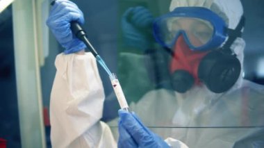 Coronavirus, COVID-19, 2019-Ncov ilaç araştırma konsepti. Bir kadın laboratuarda çalışırken tüpü sıvıyla dolduruyor..