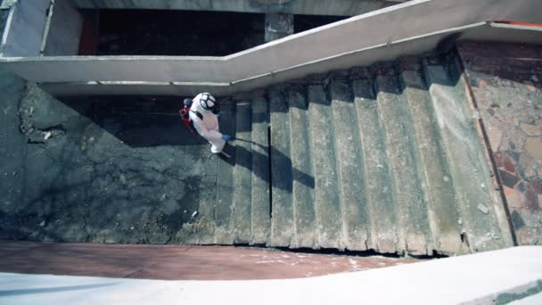 Person im Gefahrenbereich desinfiziert Treppe auf Straße. — Stockvideo