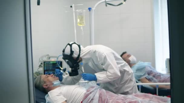 Sanitäter nehmen einem älteren Mann einen Nasenabstrich ab. Arzt in schützender Nähe von Coronavirus-Patient. — Stockvideo
