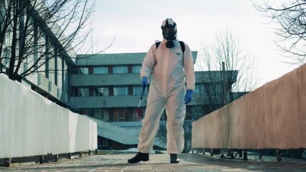 Працівник у захисному костюмі дезінфікує вулицю. Coronavirus, covid-19, 2019-ncov концепція. — стокове відео