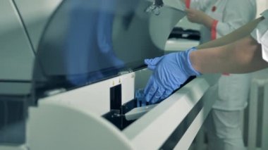 Laboratuvar çalışanı numuneleri test makinesine koyar..