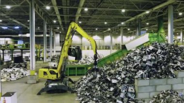 Çöpleri yükleyen bir yükleyicinin olduğu bir hurdalık. Geri dönüşüm endüstrisi konsepti, plastik çöp geri dönüşüm fabrikası.