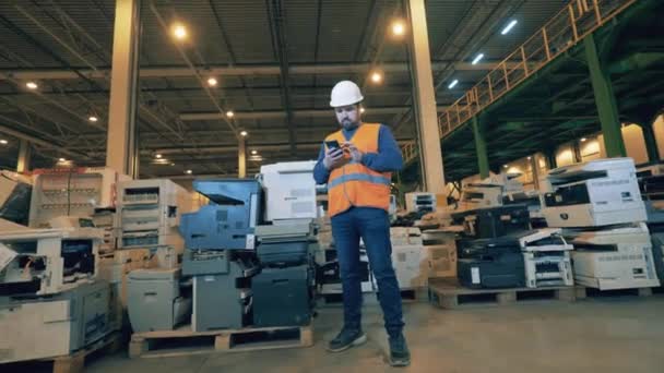 Male inspector in a unit with broken copying machines. Waste, plastic trash, garbage recycling plant. Waste, plastic trash, garbage recycling plant. — Stock Video