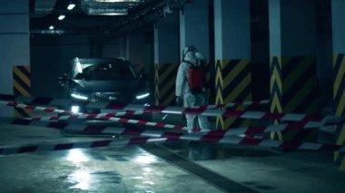 Tehlikeli maddedeki temizlik işçisi salgın sırasında bir arabayı sterilize ediyor. Coronavirus önleme, covid-19 koruyucu dezenfeksiyon.