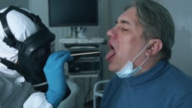 Bir doktor tarafından tutulan erkek bir hastanın boğazını muayene etmek. Enfeksiyon, covid-19 salgını, 2019-ncov konsepti.